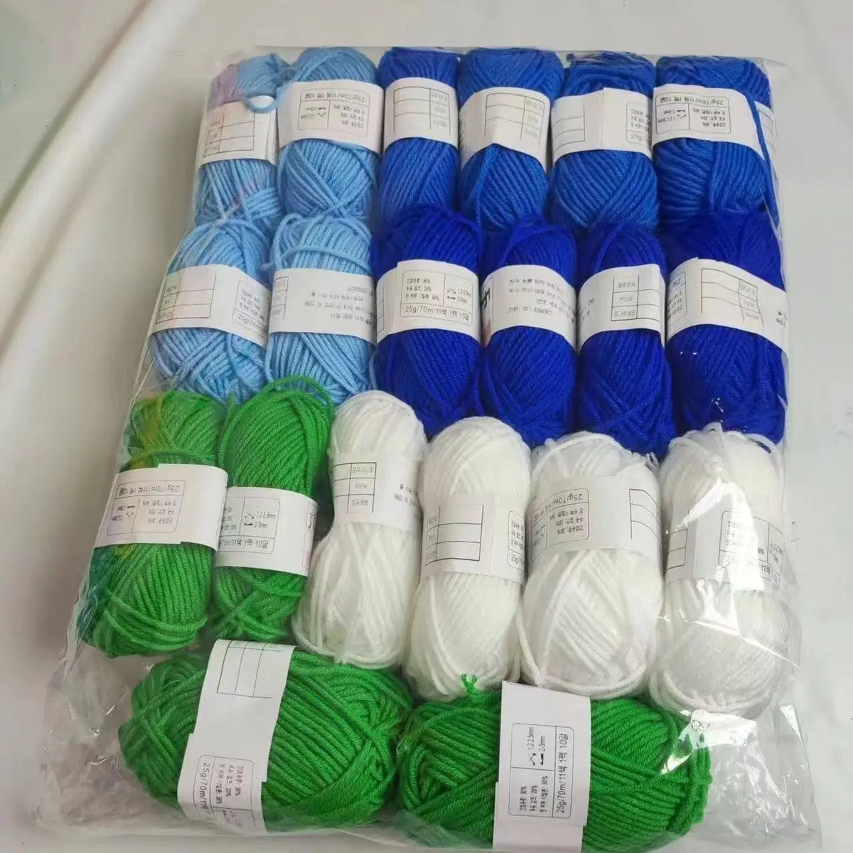 A pack of various colored yarn skeins including blue, green, and white acrylic wool for knitting and crafts