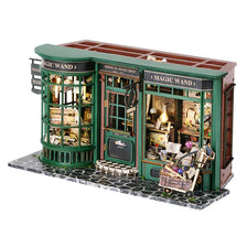 A miniature dollhouse shop set featuring a green wooden building with glass windows and various items.