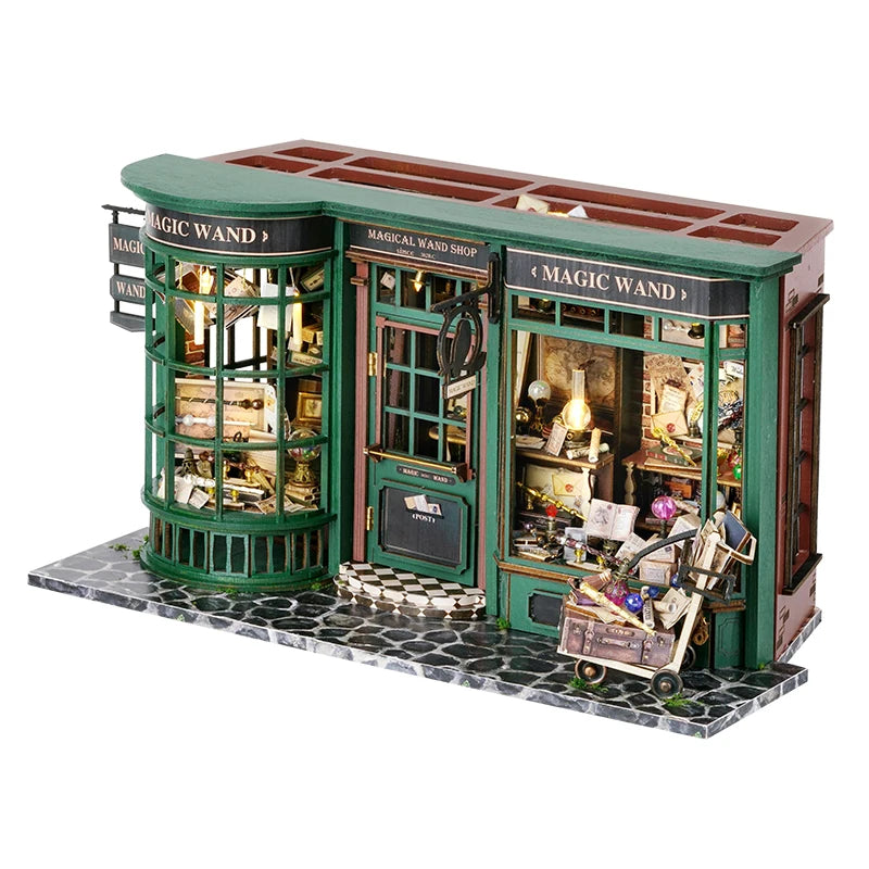 A miniature dollhouse shop set featuring a green wooden building with glass windows and various items.
