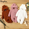 Three knitted baby rompers in brown, pink, and white with hoods displayed on a wooden surface.