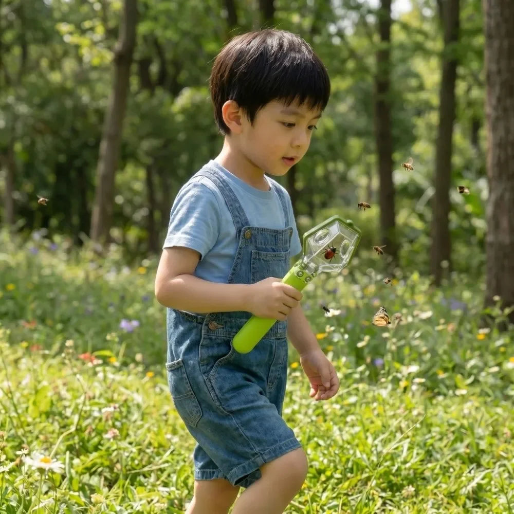 A young boy is outdoors catching insects with a handheld insect catcher.