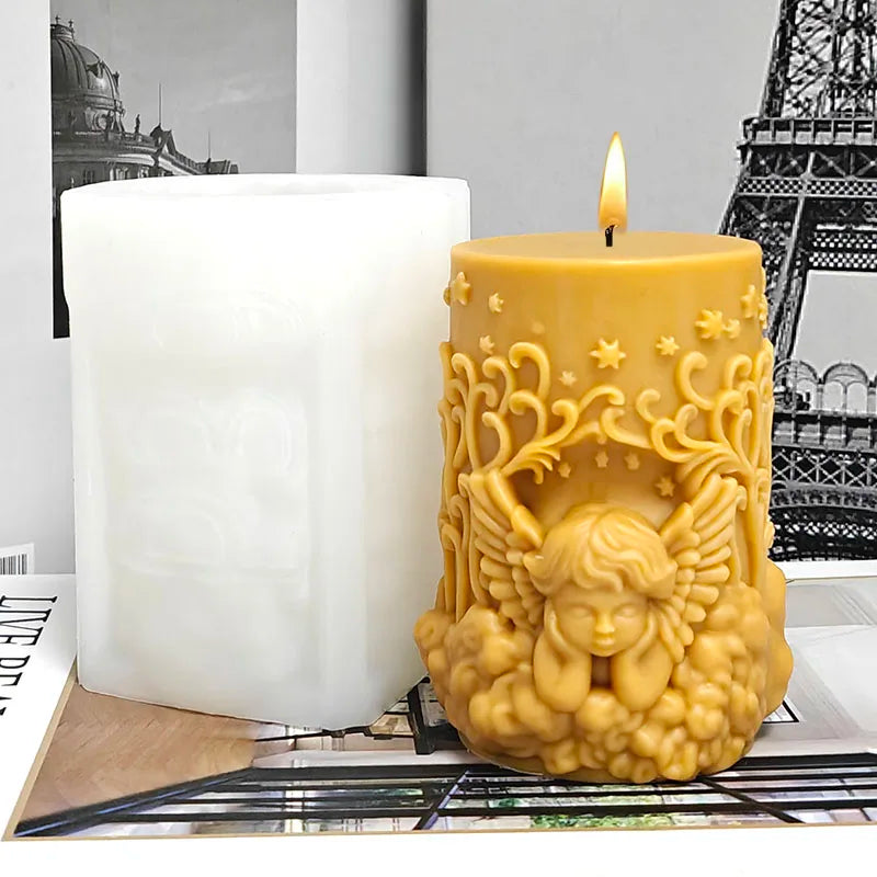 A golden silicone mold shaped like an angel is shown next to a white pillar candle.