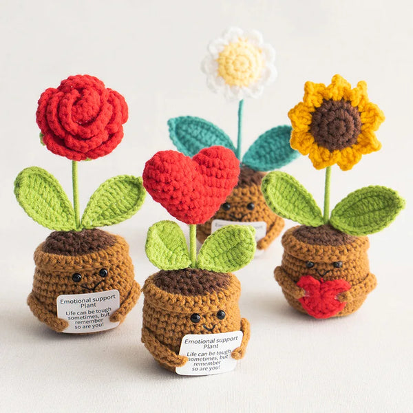 Handmade crochet emotional support plants featuring red and yellow flowers growing from brown soil.