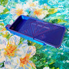 A purple diamond painting organizer tray with storage compartments resting on a green and yellow floral background.