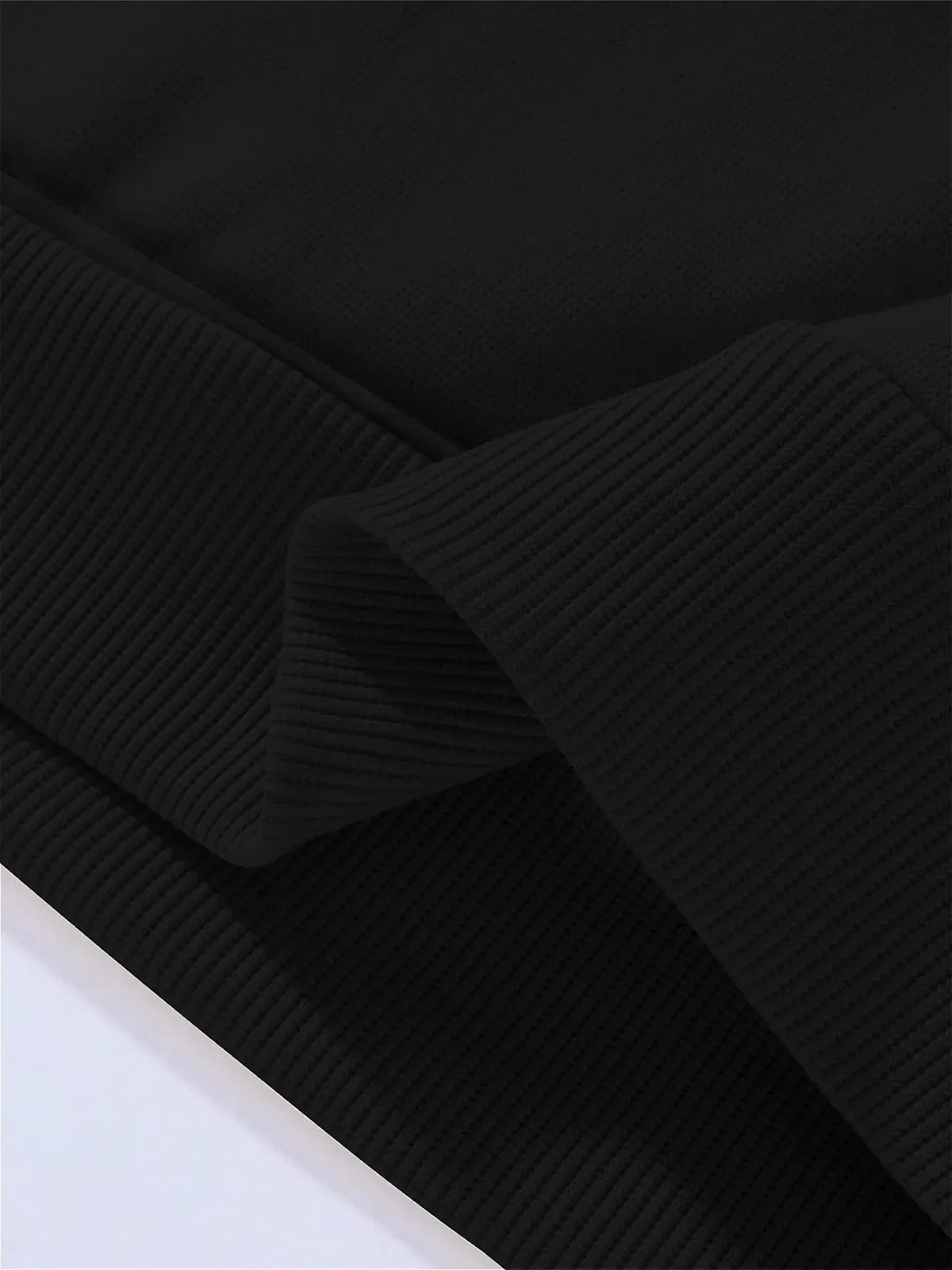 Black ribbed pullover hoodie shown in a close-up, folded texture.