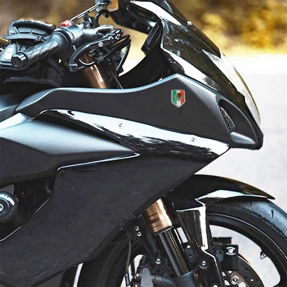 Close-up of a black motorcycle fairing featuring a 3D chrome Mexican flag emblem decal.