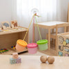 A wooden sensory activity board for toddlers featuring gears, switches, and LED lights suspended by strings.