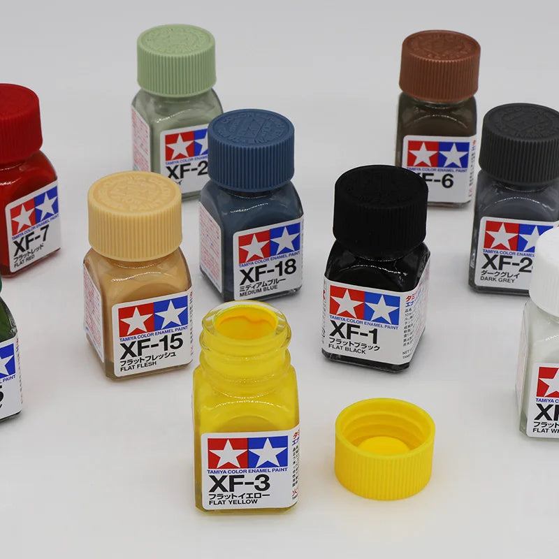 A collection of Tampiya Color Enamel paints labeled XF-7 through XF-18 in various bottles and caps.