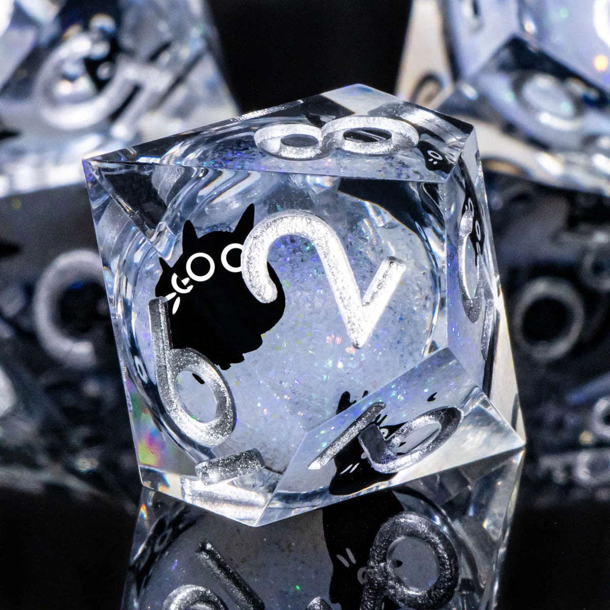A close-up of a clear resin die showing the number 2 and a cat silhouette, part of an RPG gaming set.
