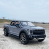 A dark gray 1:20 scale Ford Raptor F150 diecast model truck parked on a light gray surface.