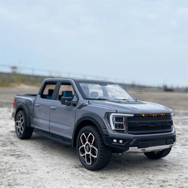 En mørkegrå Ford Raptor F150 i 1:20 skala diecast modelbil parkeret på en lysegrå overflade.