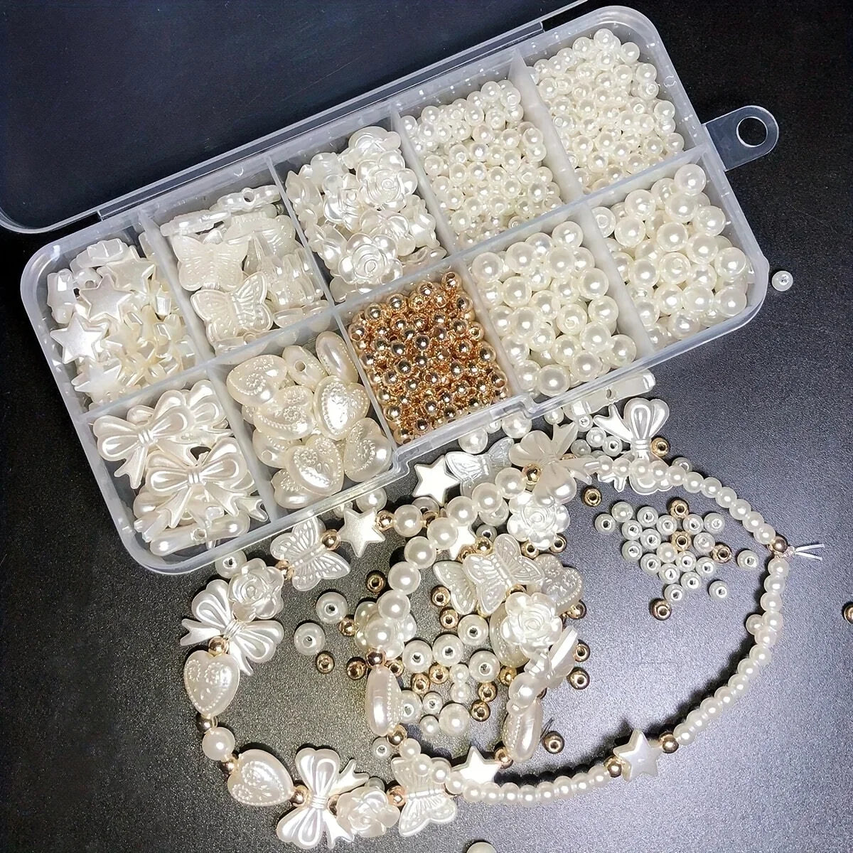 A clear plastic box filled with various white and gold acrylic pearl beads for jewelry making.
