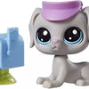 A gray dog figure with a pink hat sits next to a blue pet house toy.