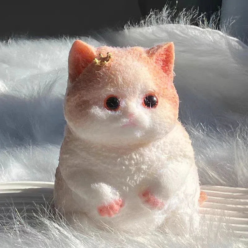 A small, fluffy orange and white cat flocking toy with gold accents sitting on a white surface.