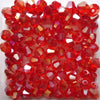 A pile of faceted red glass bicone beads for jewelry making.