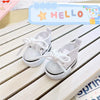 White casual sneakers with white laces and soles displayed on a wooden surface.