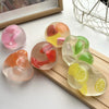 A collection of translucent squishy stress balls shaped like various fruits, including watermelon, peach, and lemon.