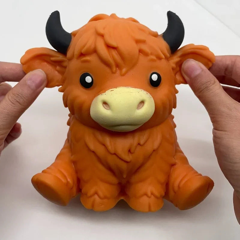 An orange jumbo highland cow squishy stress ball fidget toy being held by a person.