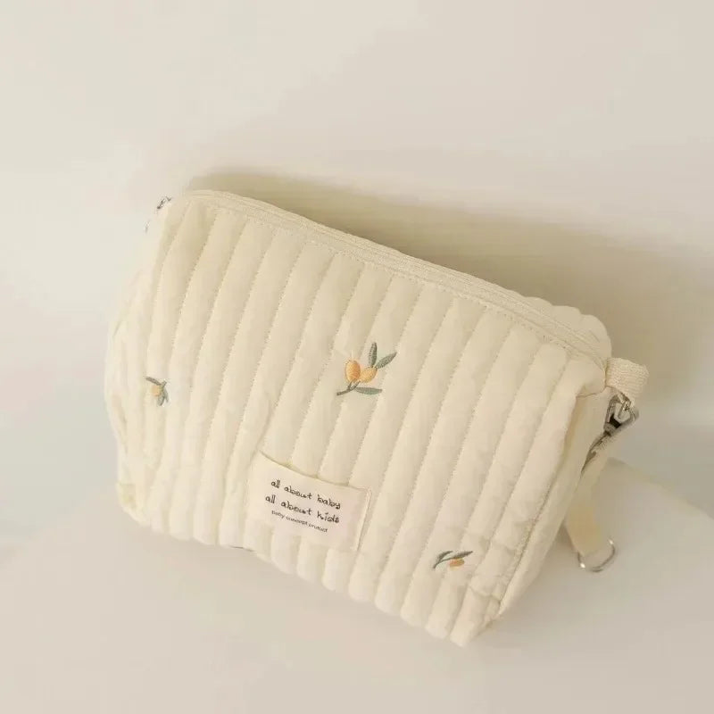 A cream quilted baby diaper caddy organizer with stroller straps.