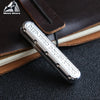 A silver metal fidget slider labeled Deep Fried Dough Sticks resting on a brown leather notebook.