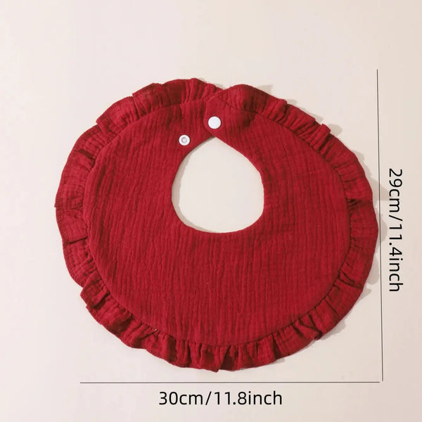 A deep red cotton baby bib with a ruffled edge and a circular cutout, shown against a white background.