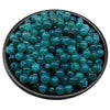 A pile of small, round, teal-blue acrylic beads for jewelry making.