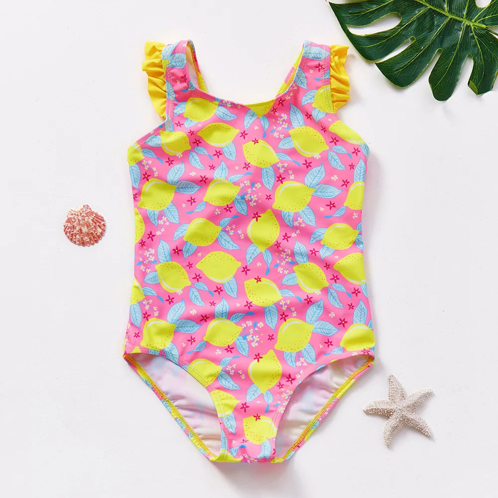 Pink and yellow mermaid unicorn one-piece swimsuit with ruffled trim, laid on a white surface.