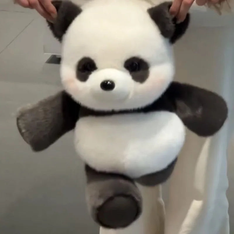 A white and black panda stuffed animal is being held up against a light background.
