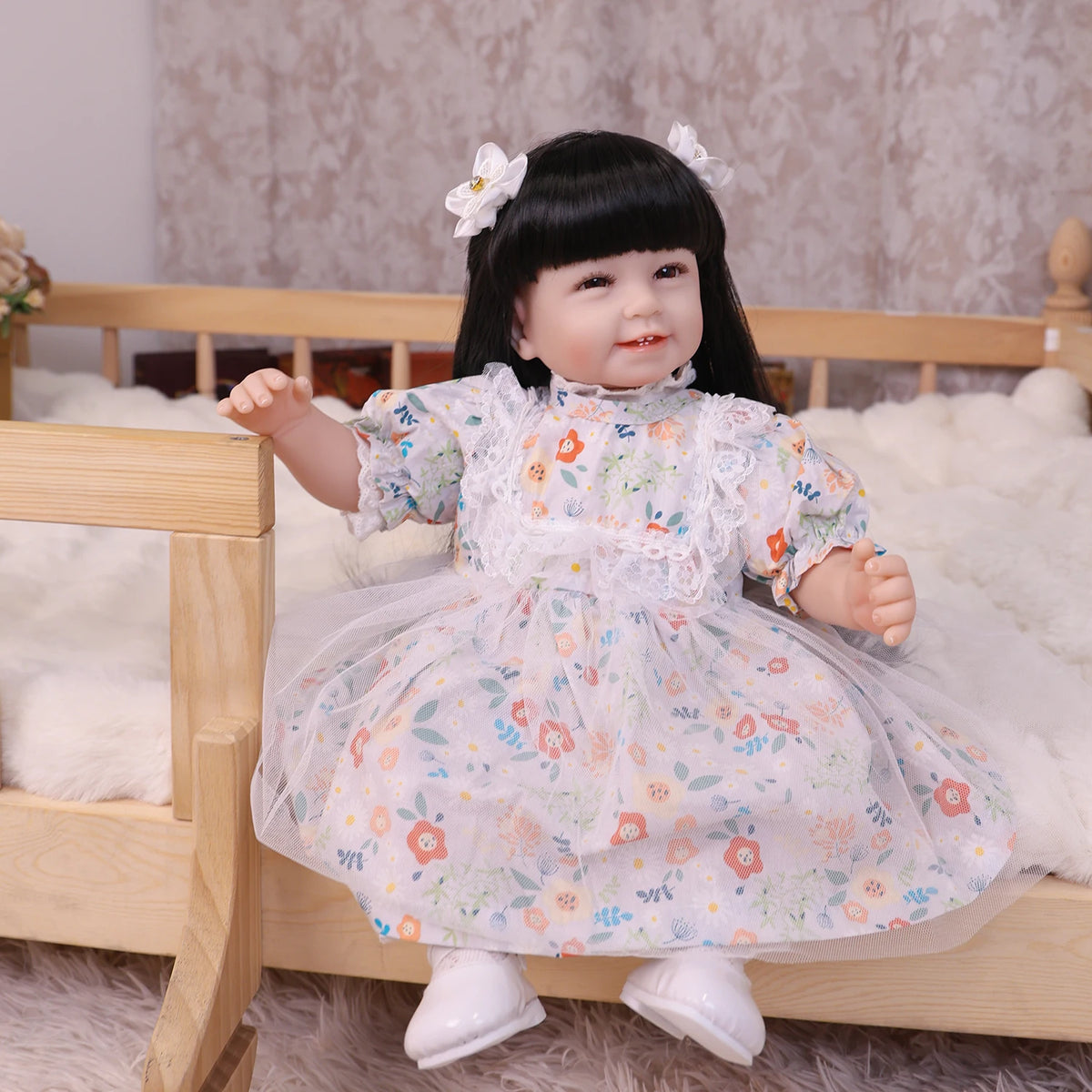 A baby doll with soft cloth body wearing a floral dress and hair accessories, posed in a wooden crib.