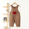 Toddler corduroy overalls in brown with a red heart embroidery hanging on a wooden hanger.