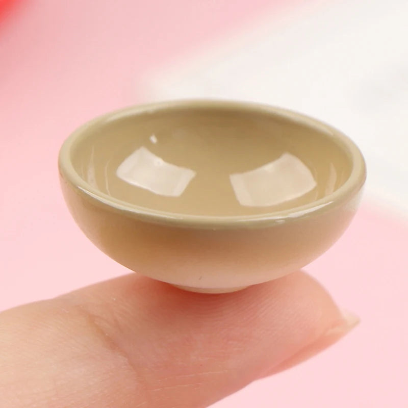 A small, beige ceramic rice bowl is held by a hand against a light pink background.