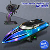 A transparent colorful LED RC boat and its remote control are shown on a gray surface.