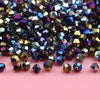 A pile of iridescent, faceted crystal glass beads in various shades of blue, purple, and gold.