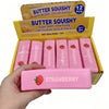 A hand holds a pink squishy strawberry stress relief toy from a box labeled Butter Squishy.