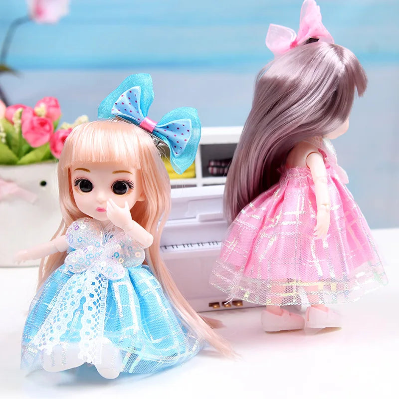A 17cm articulated princess doll with long pink hair and a sparkly blue dress, featuring a bow in her hair.