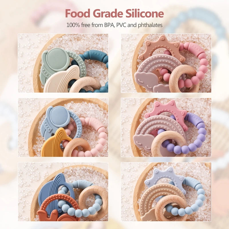 Assortment of food-grade silicone planet teethers in various colors and shapes arranged on a wooden surface.