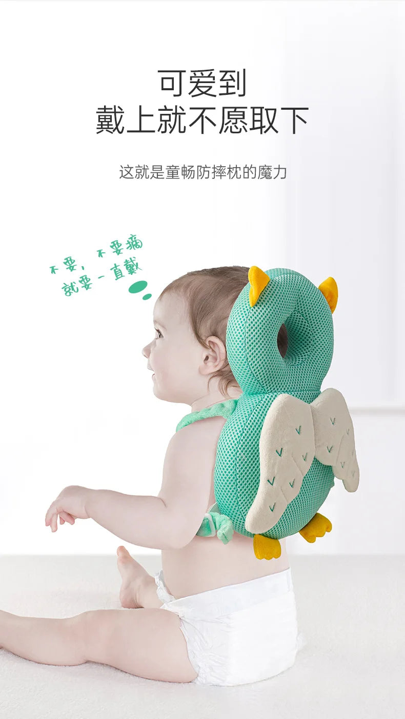 A baby is sitting and holding a soft, green elephant-shaped pillow backpack designed for security.