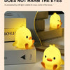 A yellow cartoon duck night light illuminating a wooden shelf in a modern home setting.
