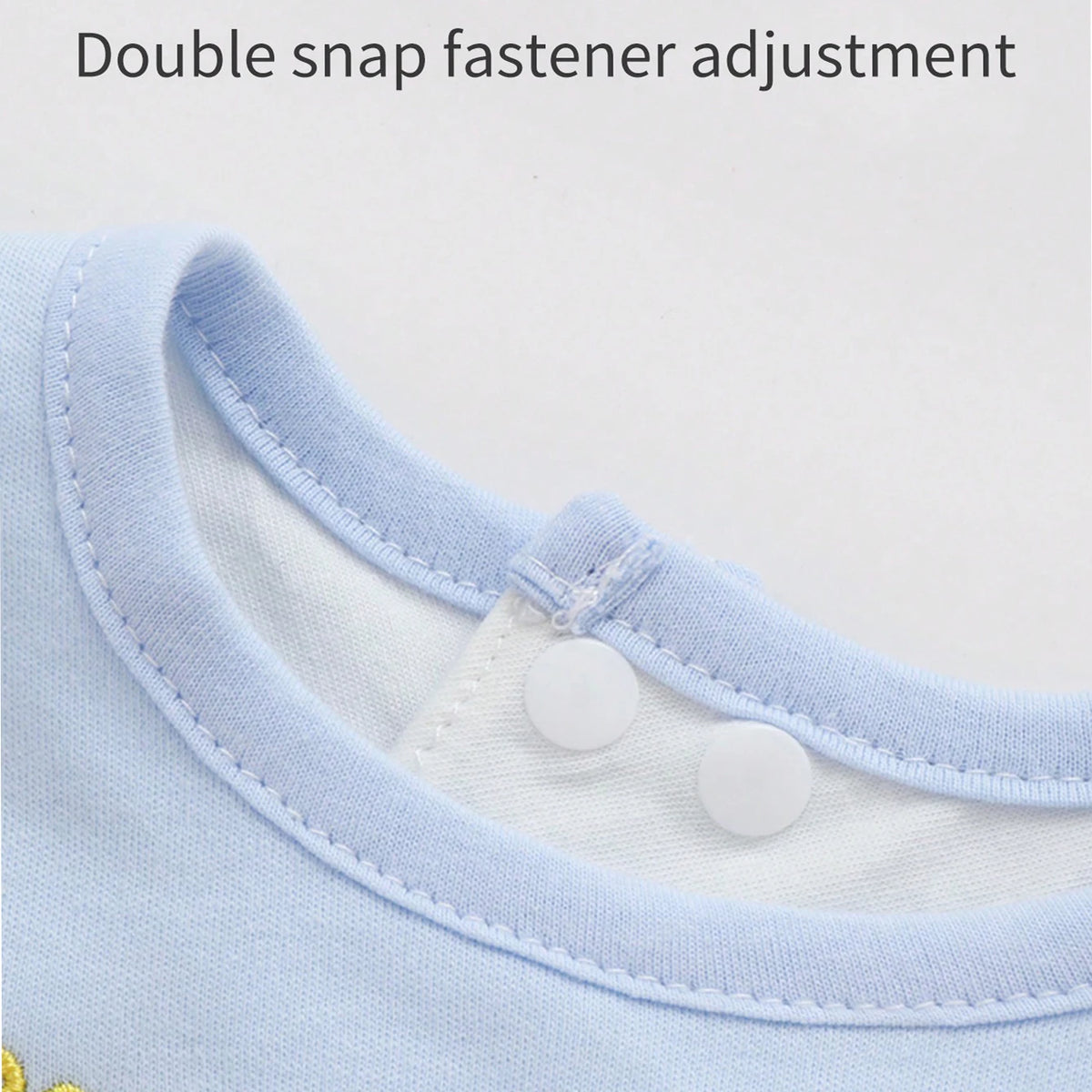 Close-up of a light blue baby bib showing a double snap fastener adjustment feature.