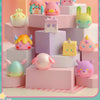 A collection of colorful geometric monster mini bean blind box figures displayed on pink and white hexagonal platforms.