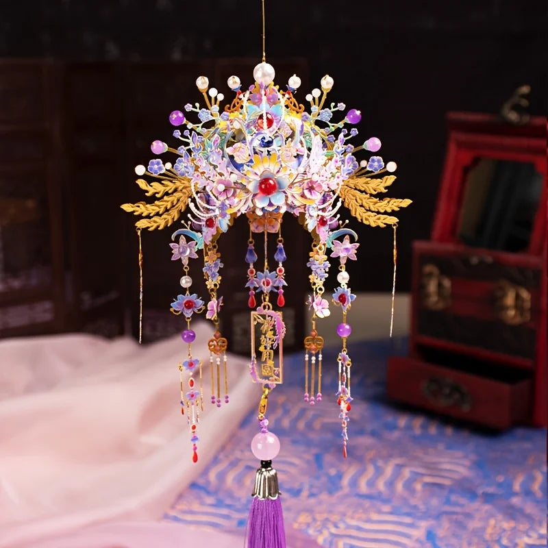 A detailed 3D metal phoenix crown model kit with colorful jewels and feathers displayed on a purple fabric.