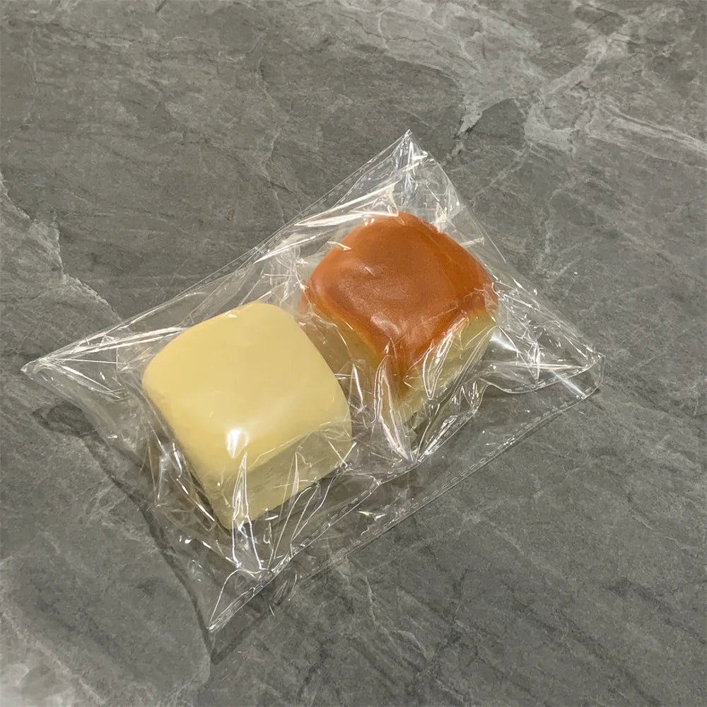 Un sac plastique transparent contient deux jouets de pains décoratifs doux, un jaune et un orange.