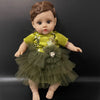 A lifelike 14-inch reborn baby doll with a green and gold outfit sitting against a dark background.