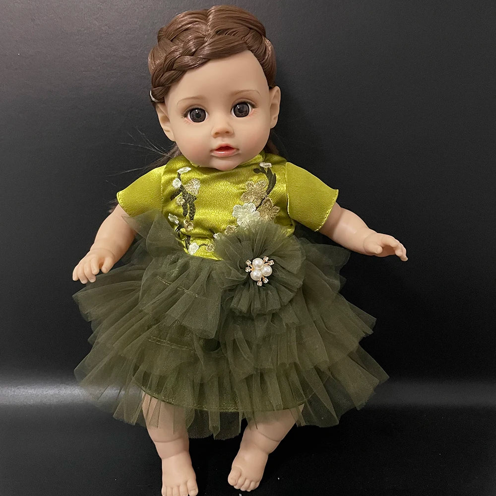A lifelike 14-inch reborn baby doll with a green and gold outfit sitting against a dark background.
