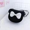 Black kids' hard shell crossbody bag with mouse ears and a white bow resting on a white textured surface.