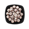 A black dish filled with small, round, printed silicone beads in leopard and daisy patterns.
