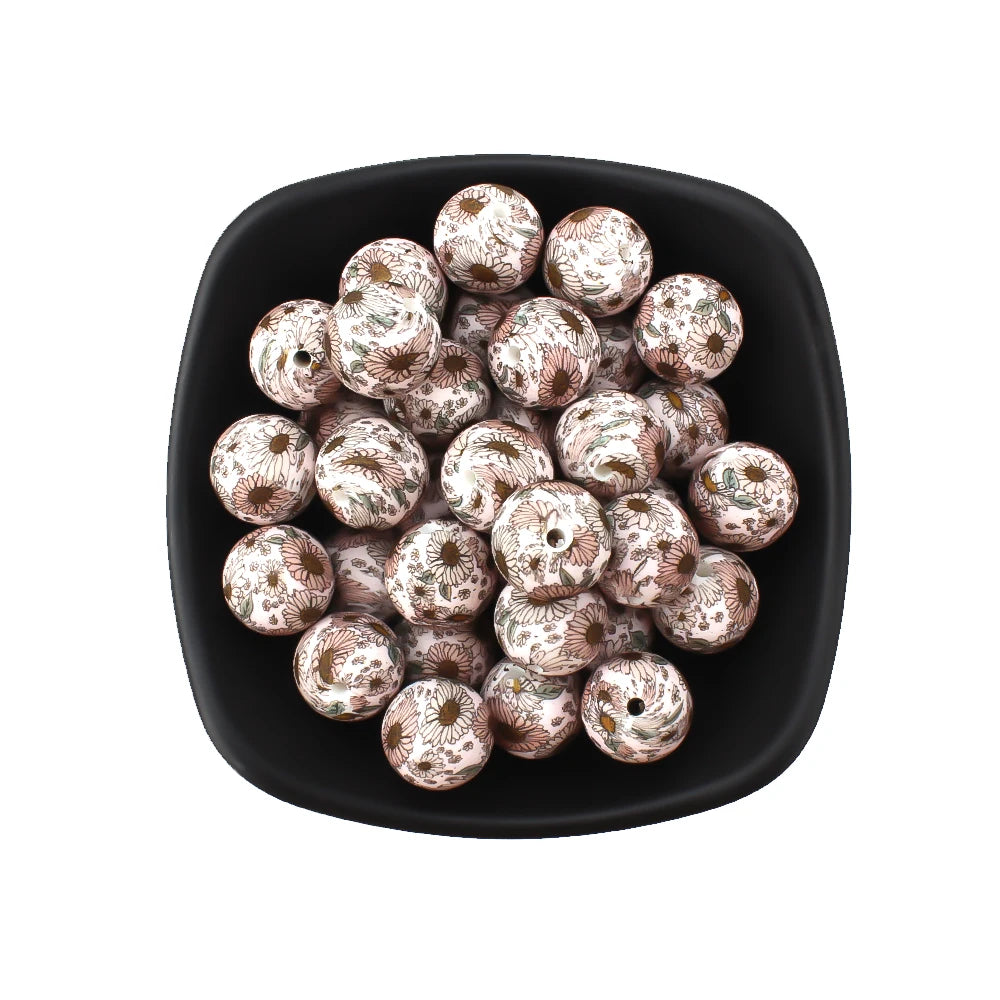A black dish filled with small, round, printed silicone beads in leopard and daisy patterns.