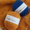 A blue and orange ball of wool yarn with labels showing Woolyarn for knitting.