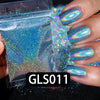 A hand holds a small plastic bag of holographic rainbow nail glitter and several manicured nails displaying the iridescent fi