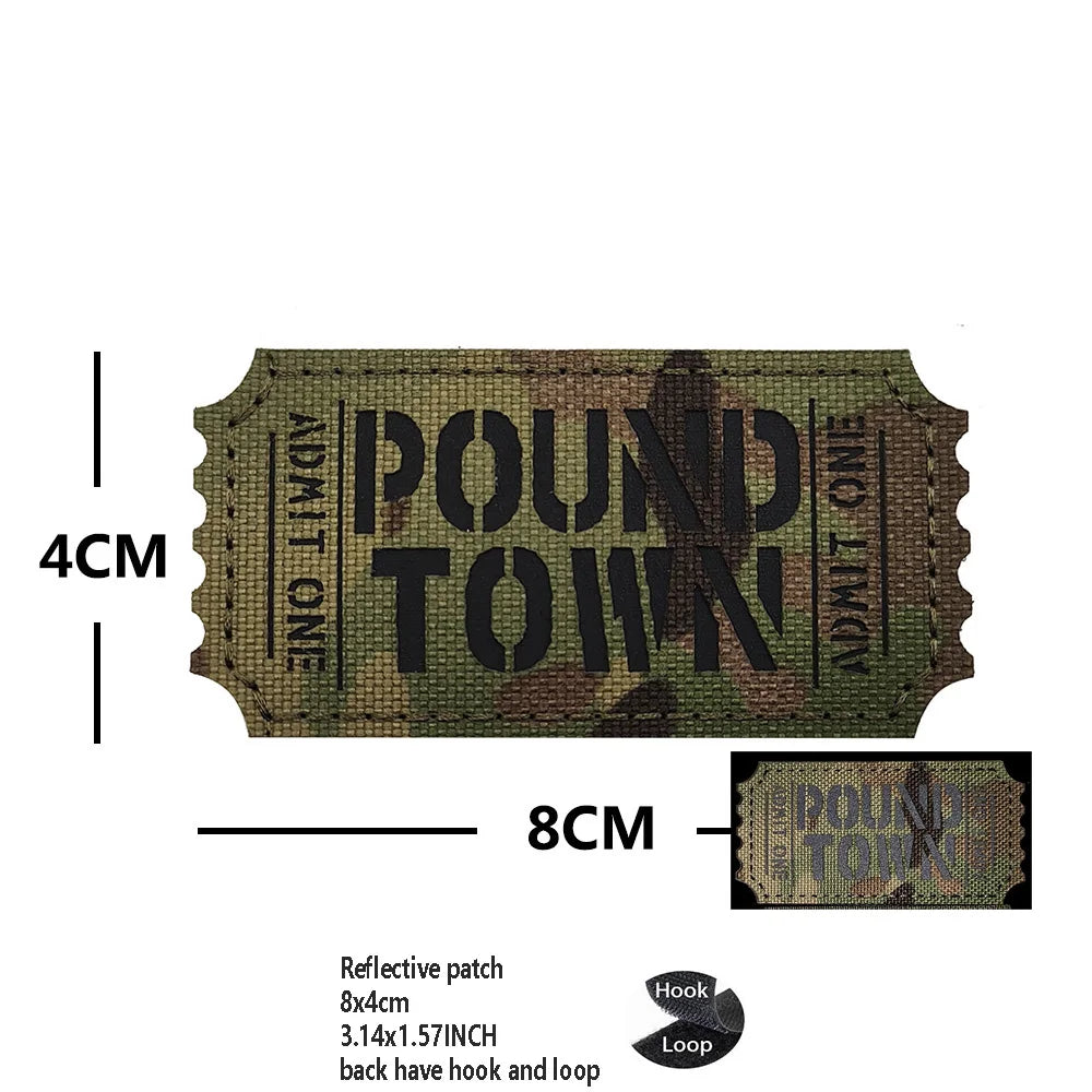 A rectangular olive green reflective patch with the text POUND TOWN and dimensions 4cm by 8cm.